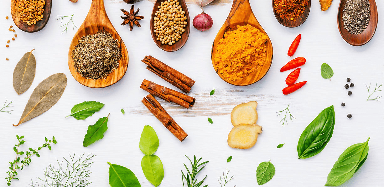 A table topped with spices and herbs on top of a white surface.