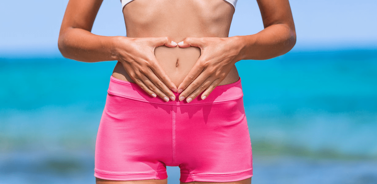 A woman in pink shorts is holding her stomach