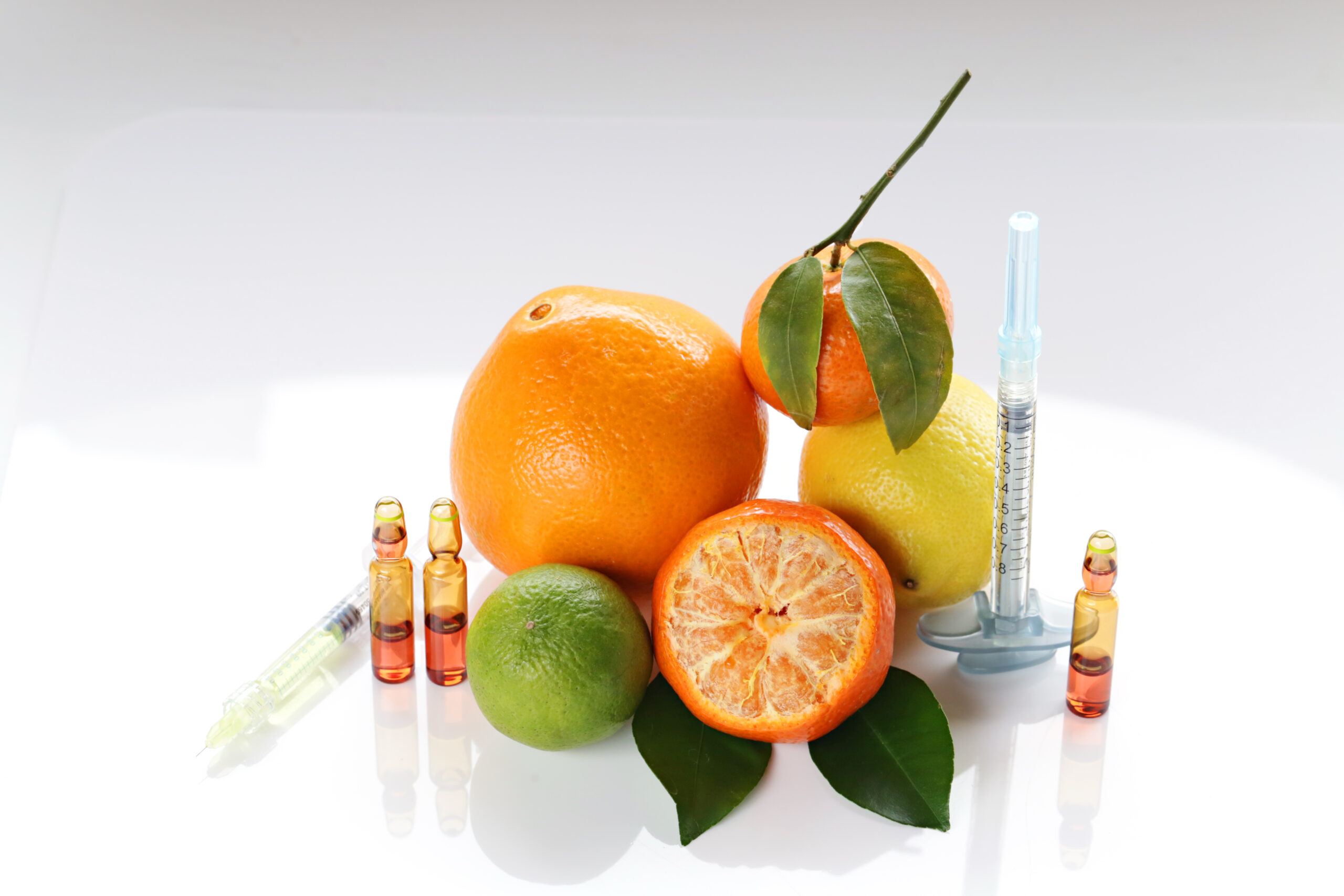 A group of fruits and a syringe on top of a table.