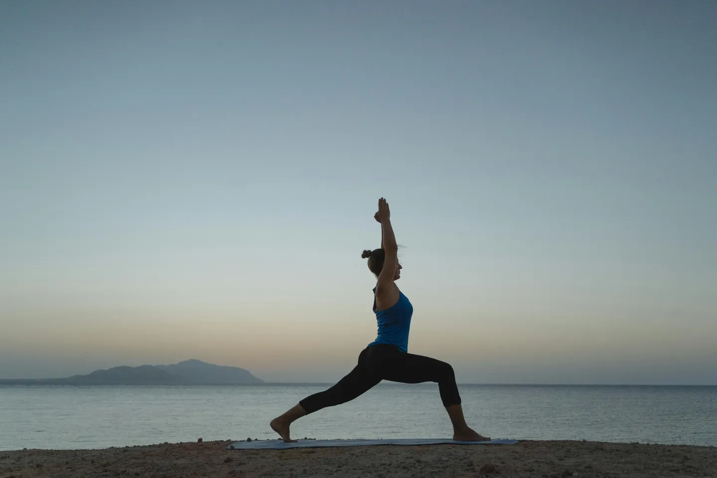 A woman is doing yoga on the beach