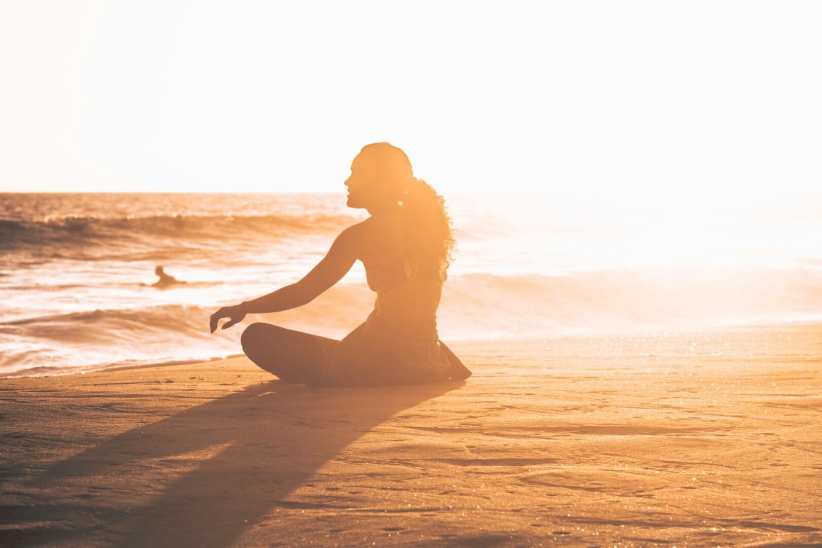 A woman doing yoga on the beach.