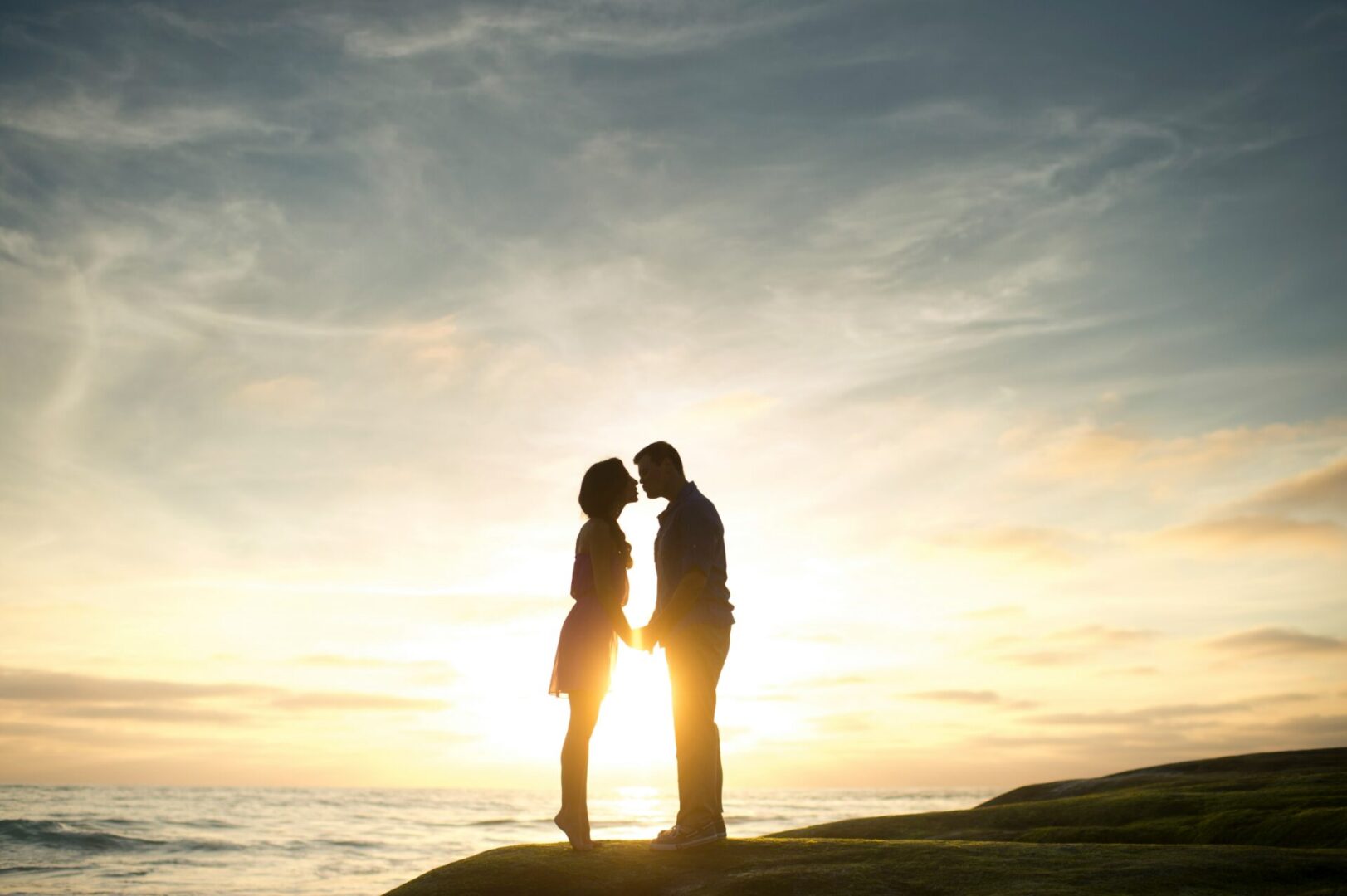 A couple on a cliff at sunset.